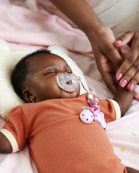 Matka dotykająca ręki śpiącego noworodka