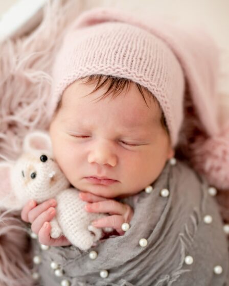 Śliczny noworodek z zabawką w malutkich rączkach